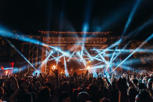 A crowd enjoys a light show at an evening festival event