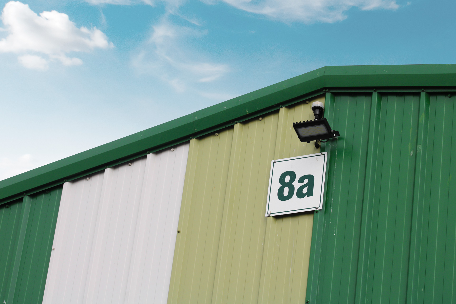 A green industrial building with lighting and a plaque denoted with 8a